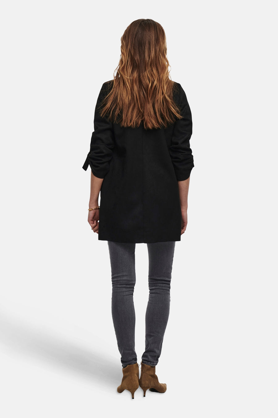 Veste longue noire de ONLY, avec des manches retroussées, portée avec un jean gris et des bottines marron.
