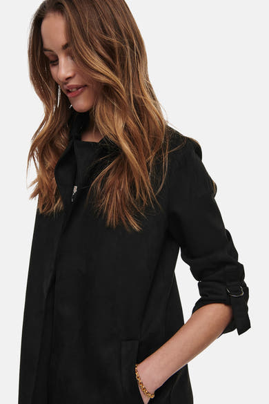 Veste longue noire de ONLY, avec manches trois-quarts et poche latérale, portée avec un bracelet doré.
