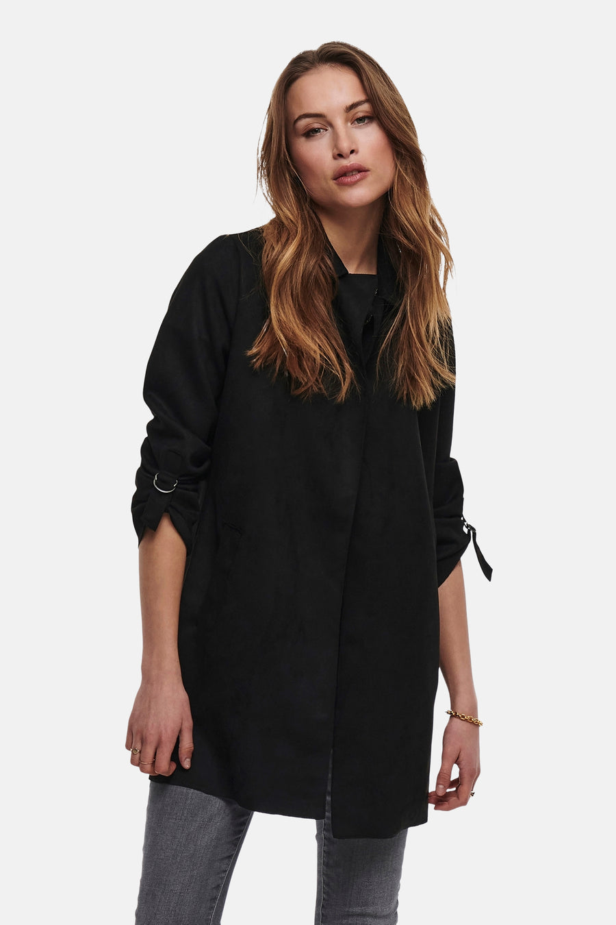 Veste longue noire de ONLY, avec manches trois-quarts à anneaux, portée avec un jean gris et des bijoux dorés.