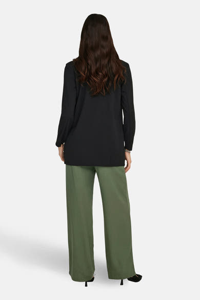 Zwarte blazer van JDY, met lange mouwen, gedragen met een wijde groene broek en zwarte hakken.