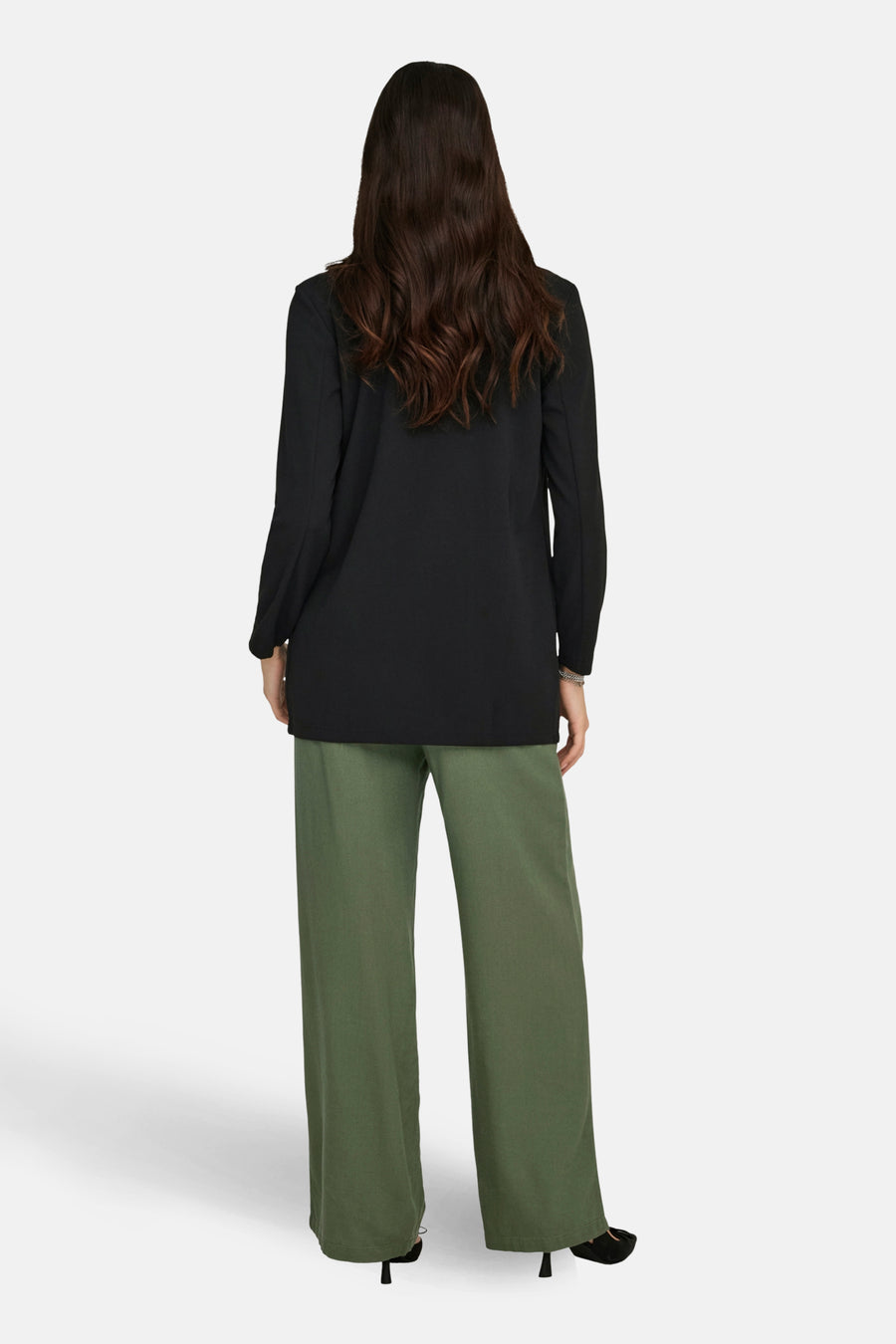 Zwarte blazer van JDY, met lange mouwen, gedragen met een wijde groene broek en zwarte hakken.