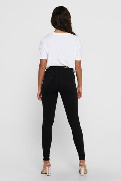 Jean skinny noir de ONLY, porté avec un t-shirt blanc et des talons transparents, vue de dos.
