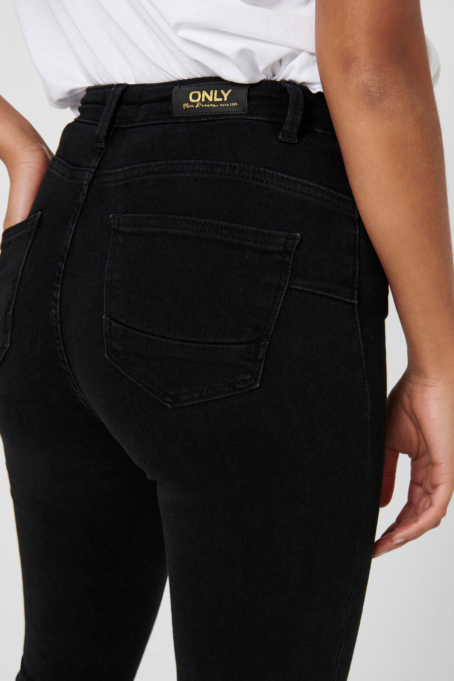 Jean skinny noir de ONLY, vue arrière avec poche, porté avec un t-shirt blanc.