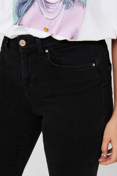 Jean skinny noir de ONLY, détail de la taille haute, porté avec un t-shirt imprimé.

