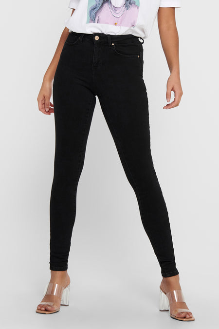 Jean skinny noir de ONLY, porté avec un t-shirt à imprimé et des chaussures à talons transparentes.
