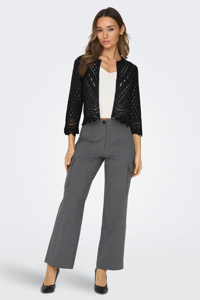 Cardigan noir en maille ajourée de JDY, porté sur un débardeur blanc avec un pantalon cargo gris et des escarpins noirs.
