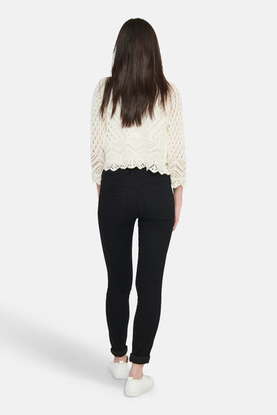 Beige cardigan van JDY in ajourbreisel met geschulpte zoom, van achteren gedragen door een vrouw in een zwarte jeans.