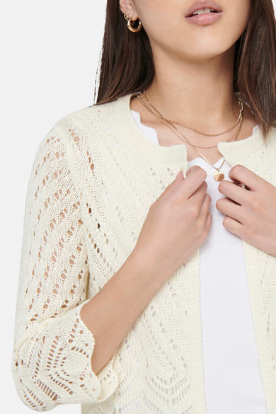 Beige cardigan van JDY in opengebreide stof, gedragen door een vrouw met een witte top en gouden kettingen.
