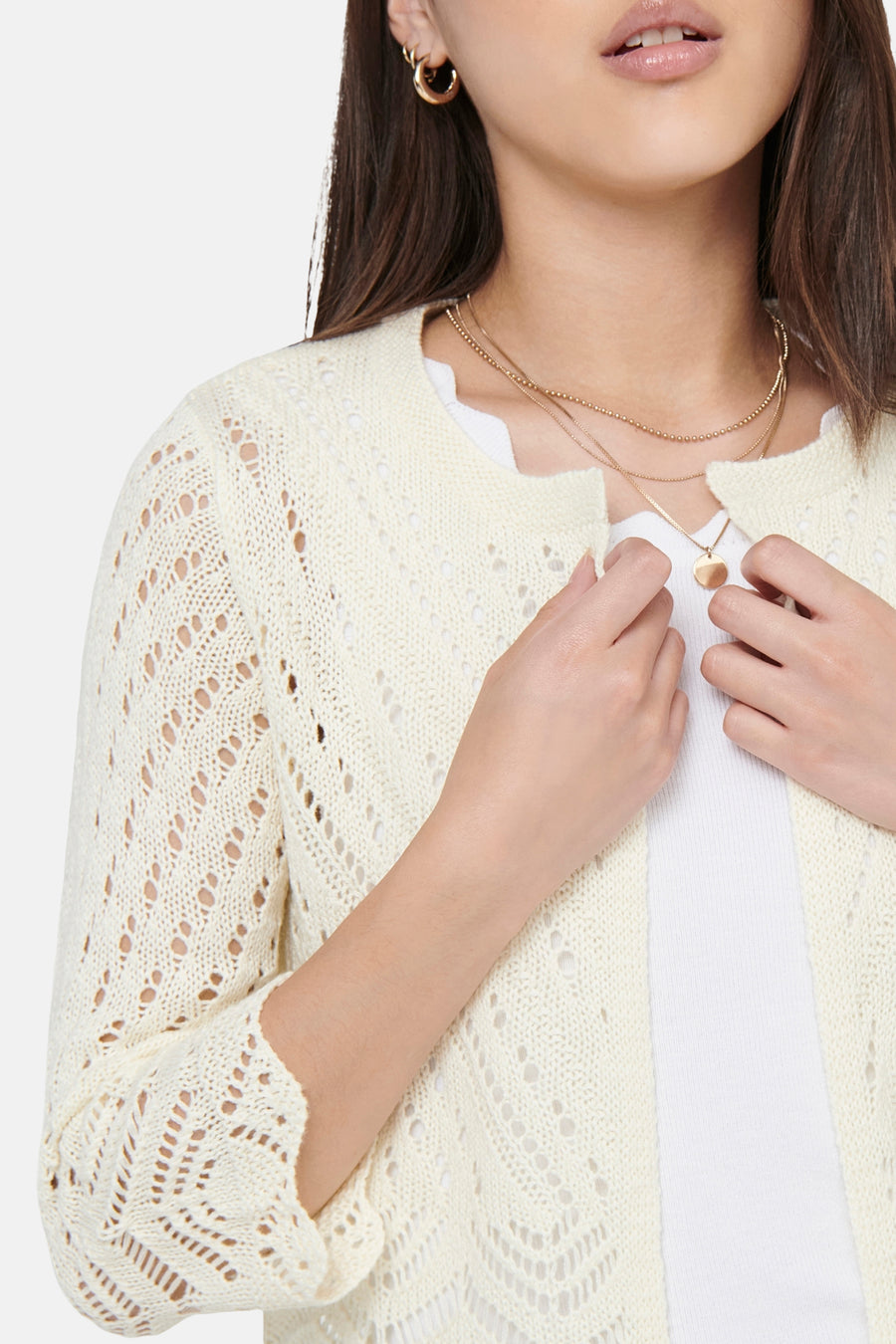 Beige cardigan van JDY in opengebreide stof, gedragen door een vrouw met een witte top en gouden kettingen.