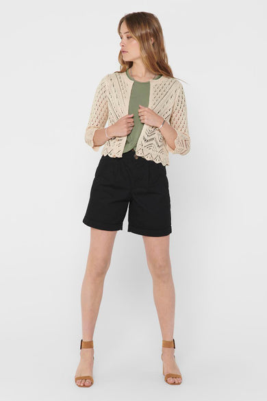 Gilet écru by JDY, à mailles ajourées, porté sur un t-shirt vert et un short noir.