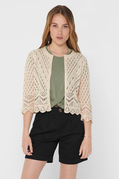 Gilet écru by JDY, en maille ajourée à manches 3/4, porté sur un t-shirt vert noué.
