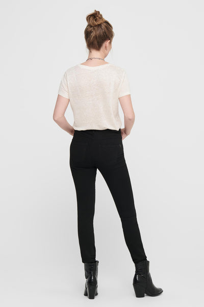 Jean skinny noir de ONLY®, porté avec un t-shirt beige et des bottines en similicuir à motif crocodile.
