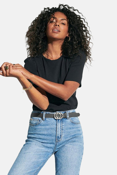 Grijze riem van ONLY®, met een zilverkleurige dubbele cirkelgesp, gedragen met een high-waisted jeans en een zwart T-shirt.