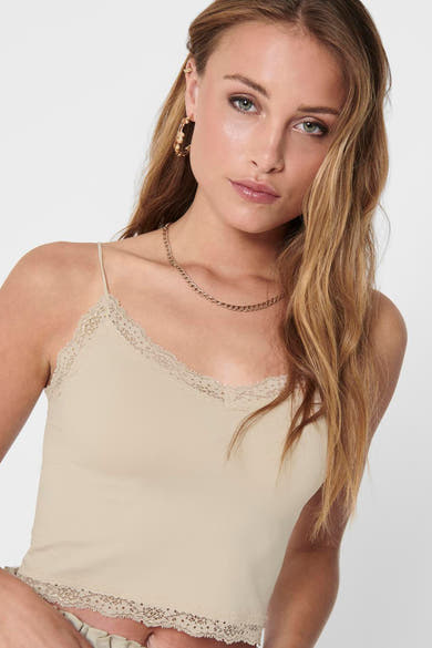 Ecru beha van ONLY, met decoratief kant bij de halslijn, gedragen met een gouden ketting en ronde oorbellen.