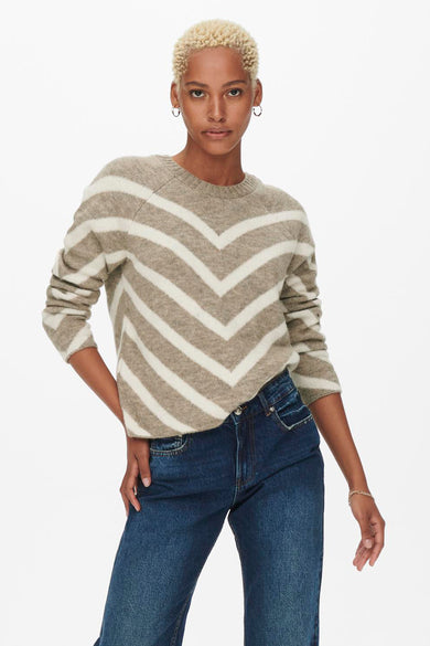 Pull beige à rayures chevron par ONLY, porté avec un jean bleu et des boucles d'oreilles créoles.
