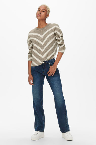 Pull beige à chevrons de ONLY, porté avec un jean bleu et des baskets blanches.