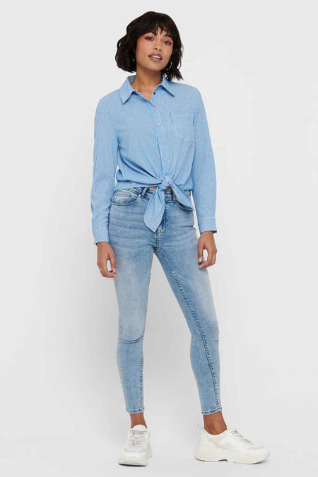Chemise bleue rayée à manches longues par ONLY, nouée à la taille, portée avec un jean et des baskets blanches.