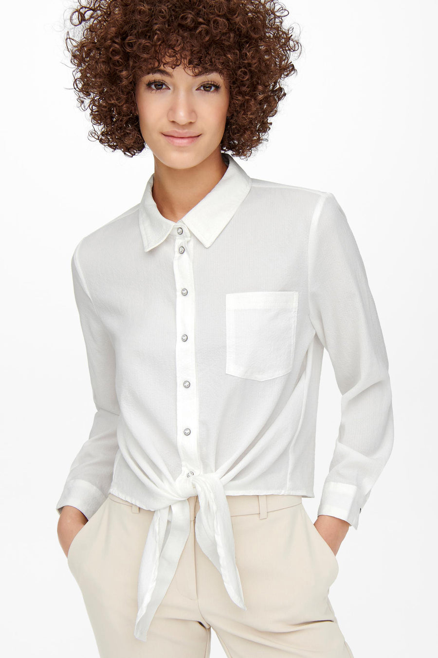 Chemisier à manches longues écru de ONLY, avec poche poitrine et noué à la taille, porté avec un pantalon beige.
