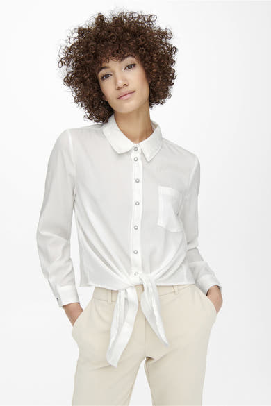 Chemisier à manches longues écru de ONLY, avec boutons argentés, poche poitrine et nœud à la taille, porté avec un pantalon beige.
