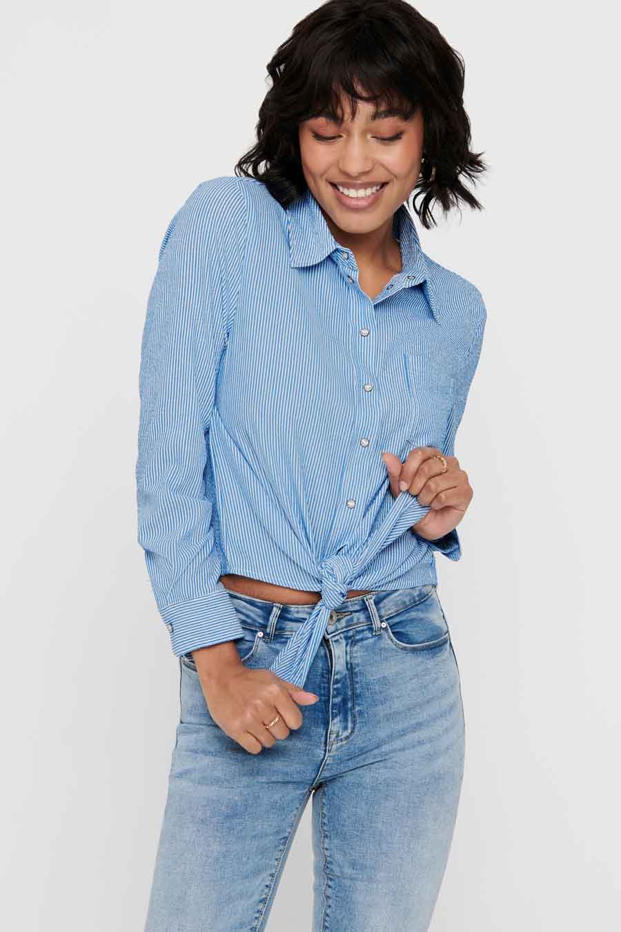 Chemise bleue rayée à manches longues de ONLY, nouée à la taille, portée avec un jean bleu.