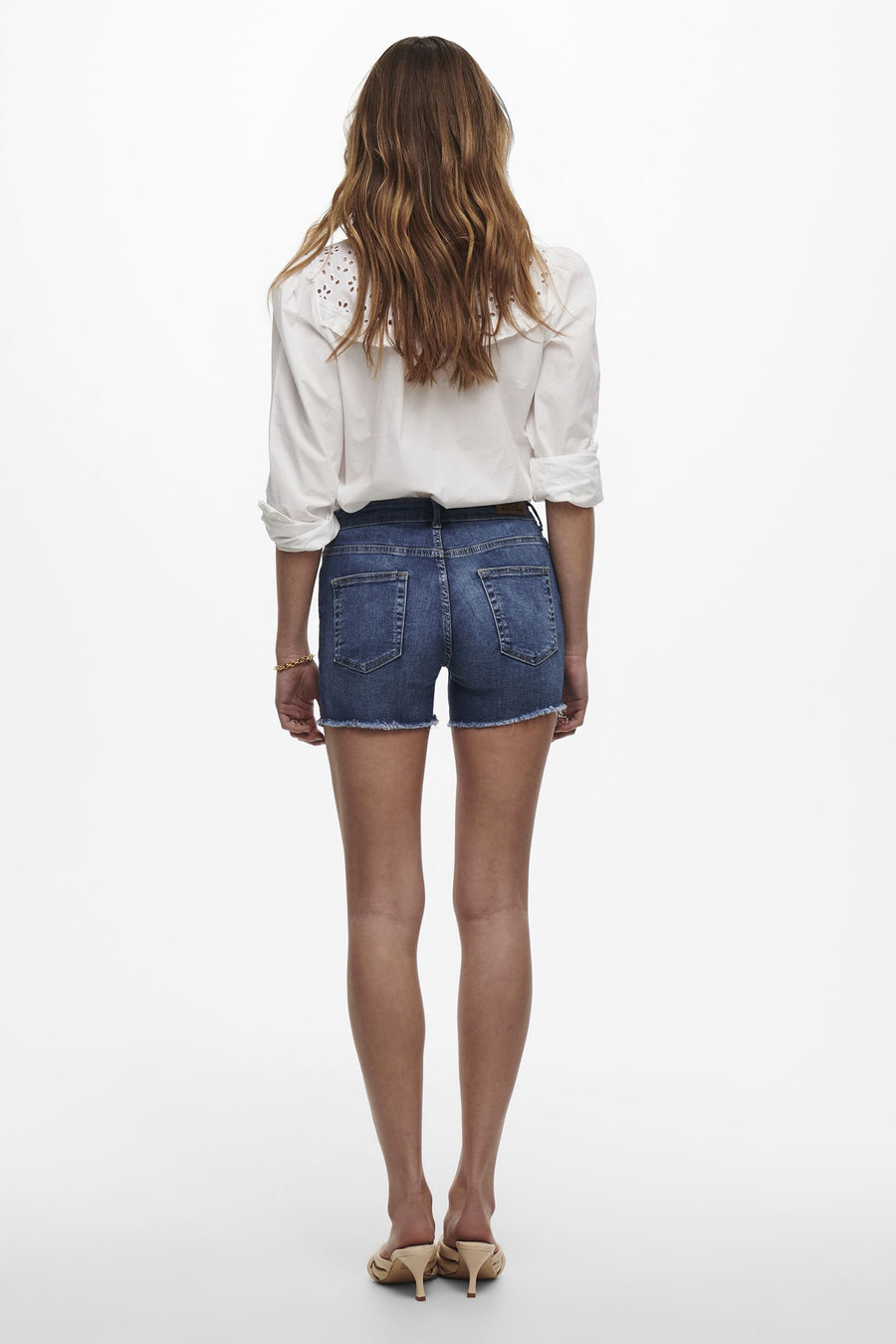 Short bleu de ONLY, porté avec une chemise blanche et des mules à talons.