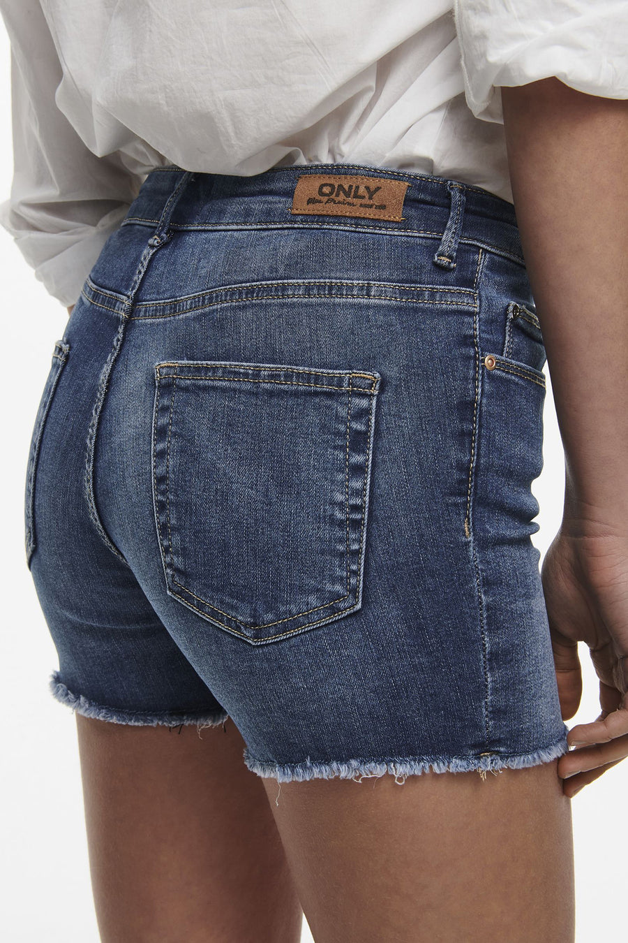 Short en jean bleu par ONLY, avec ourlet effiloché et poche arrière visible.