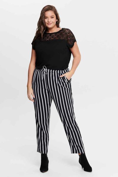 Zwarte top met korte mouwen van CARMAKOMA, met kanten inzetstuk, gedragen met een gestreepte broek en zwarte enkellaarsjes.