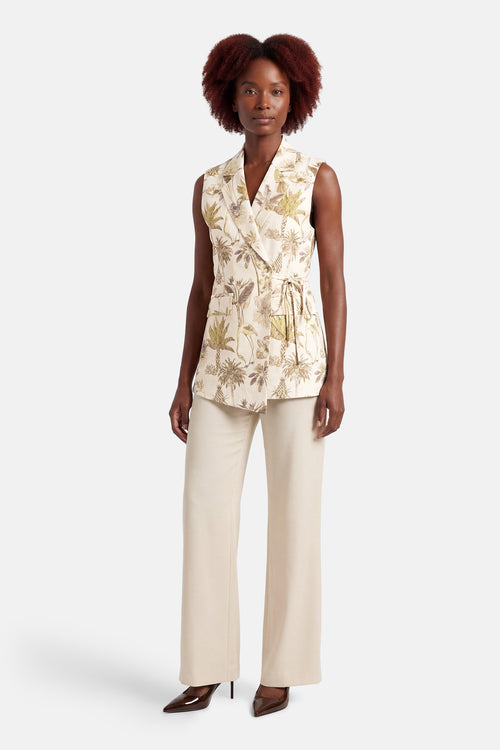 Blazer multicolore de GOA GOA, à imprimé botanique, porté avec un pantalon taille haute beige et des escarpins marron.
