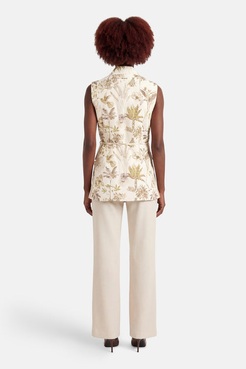 Blazer multicolore de GOA GOA avec un motif de jungle, porté avec un pantalon blanc taille haute et des talons foncés.