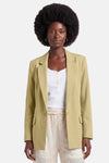 Blazer vert clair de GOA GOA, coupe droite à un bouton, avec poches à rabat, porté sur un haut blanc et un pantalon brodé.