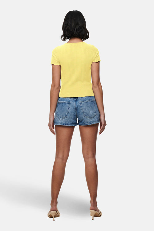 T-shirt à manches courtes jaune de ONLY, porté avec un short en jean et des talons beiges.