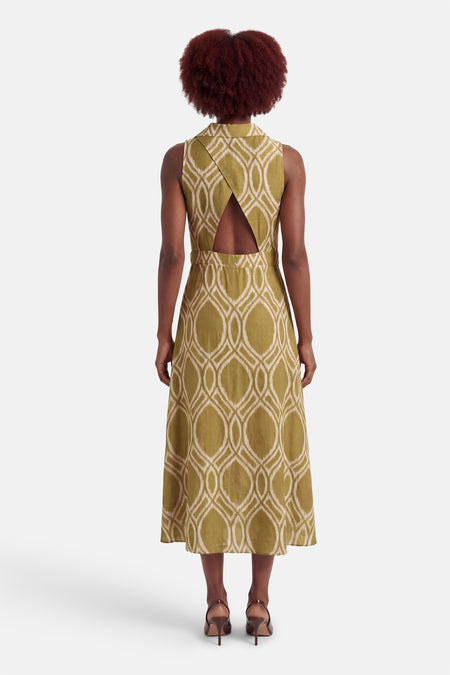 Groene jurk met geometrisch patroon van GOA GOA, halternek, midi-lengte en bruine hoge hakken.
