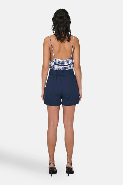 Korte blauwe short van JDY, met een hoge elastische taille, gedragen met een bloemenprint top en zwarte hak sandalen.