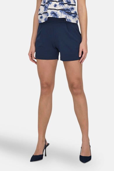 Korte blauwe short van JDY, met elastische taille, gedragen met een witte tanktop en een zwarte tas.