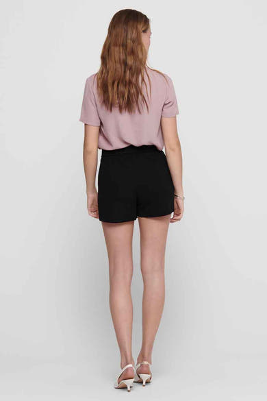 Short noir de JDY, vu de dos, porté avec un chemisier rose et des escarpins blancs.