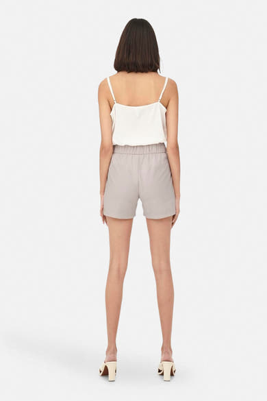 Korte grijze rok van JDY, met elastische tailleband, gedragen met een witte top met spaghettibandjes.