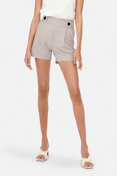 Short gris de JDY avec boutons décoratifs à la taille, porté avec un haut blanc et des mules à talons.