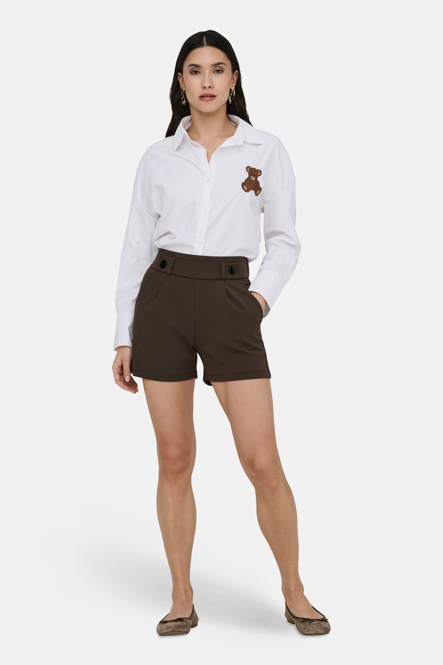 Short brun de JDY, porté avec une chemise blanche agrémentée d'un ours en peluche et des ballerines marron.
