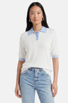 Pull polo blanc ajouré et bleu clair de GOA GOA, avec col et bords de manches rayés, porté avec un jean.