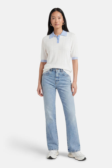 Pull en maille blanc à motif quadrillé, col polo et rayures bleu clair de GOA GOA, porté avec un jean clair.