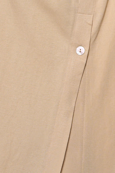 Beige blouse van GOA GOA in getextureerde stof, met een parelmoeren knoop en een overlappende plooi.