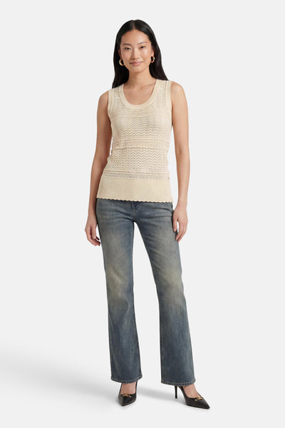 Top beige de GOA GOA en tricot sans manches, avec bandes de motifs en maille et ourlet festonné, porté avec un jean et des escarpins noirs.