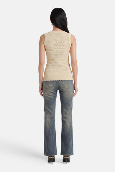 Beige mouwloze top van GOA GOA, met diverse uitgesneden patronen op de rug en een geschulpte zoom, gedragen met een spijkerbroek.