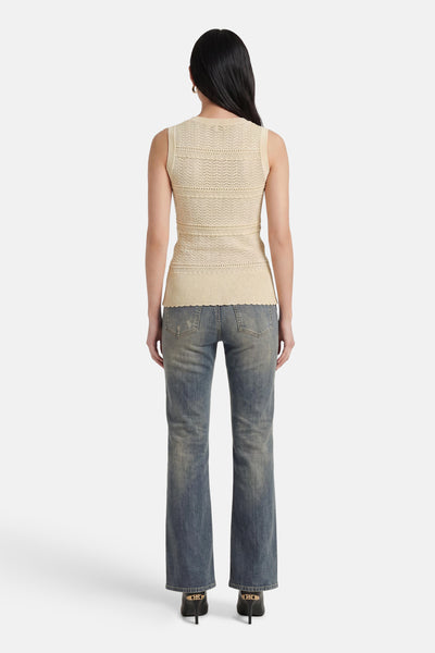 Beige mouwloze top van GOA GOA, met diverse uitgesneden patronen op de rug en een geschulpte zoom, gedragen met een spijkerbroek.