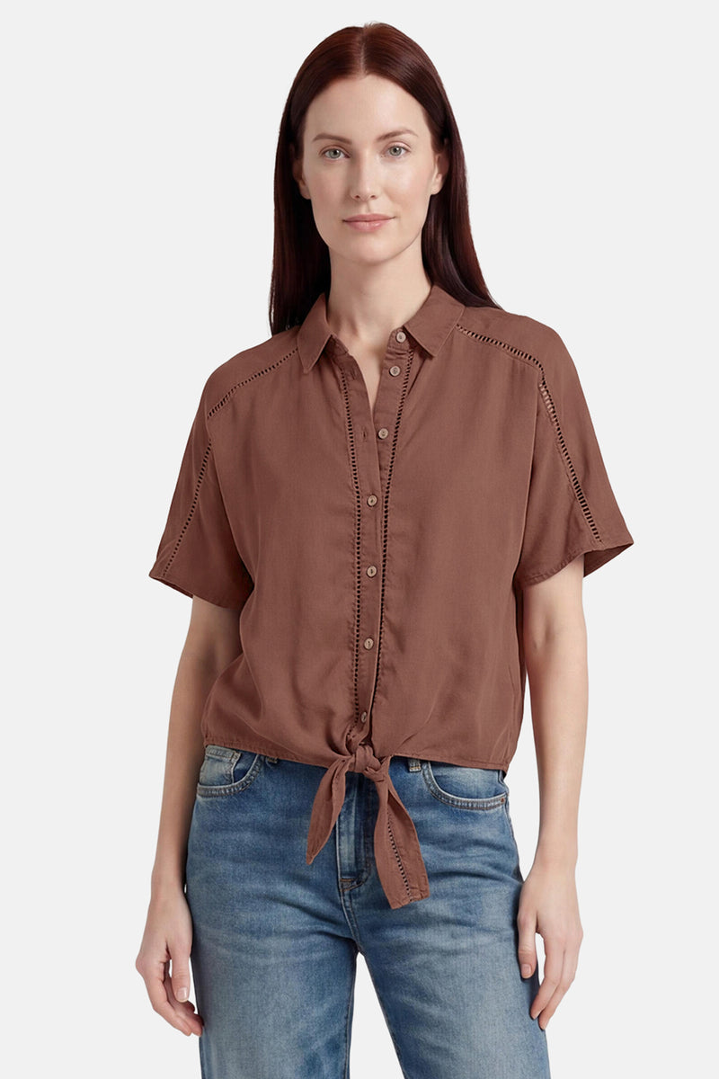 Chemisier marron à manches courtes de GOA GOA avec détails perforés, noué à la taille, porté avec un jean bleu.