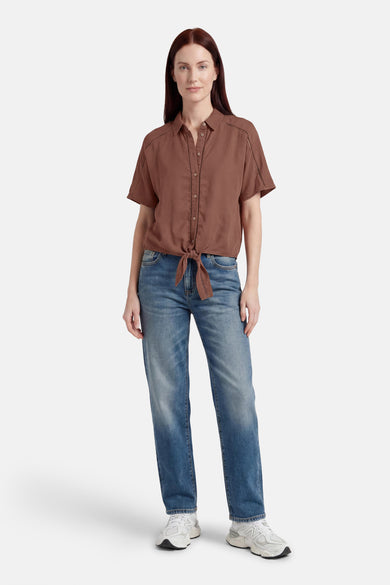 Chemisier marron à manches courtes de GOA GOA avec découpes décoratives, boutonné et noué à la taille, porté avec un jean et des baskets.