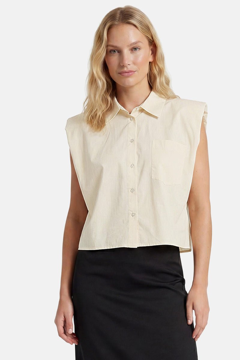 Chemisier sans manches beige de GOA GOA avec col, boutonnage, poche poitrine, porté avec une jupe noire.