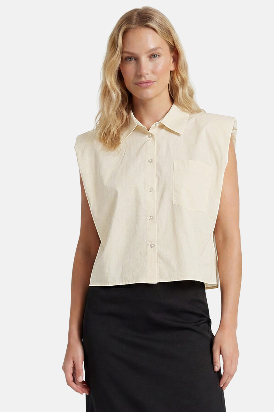 Chemisier sans manches beige de GOA GOA avec col, boutonnage, poche poitrine, porté avec une jupe noire.