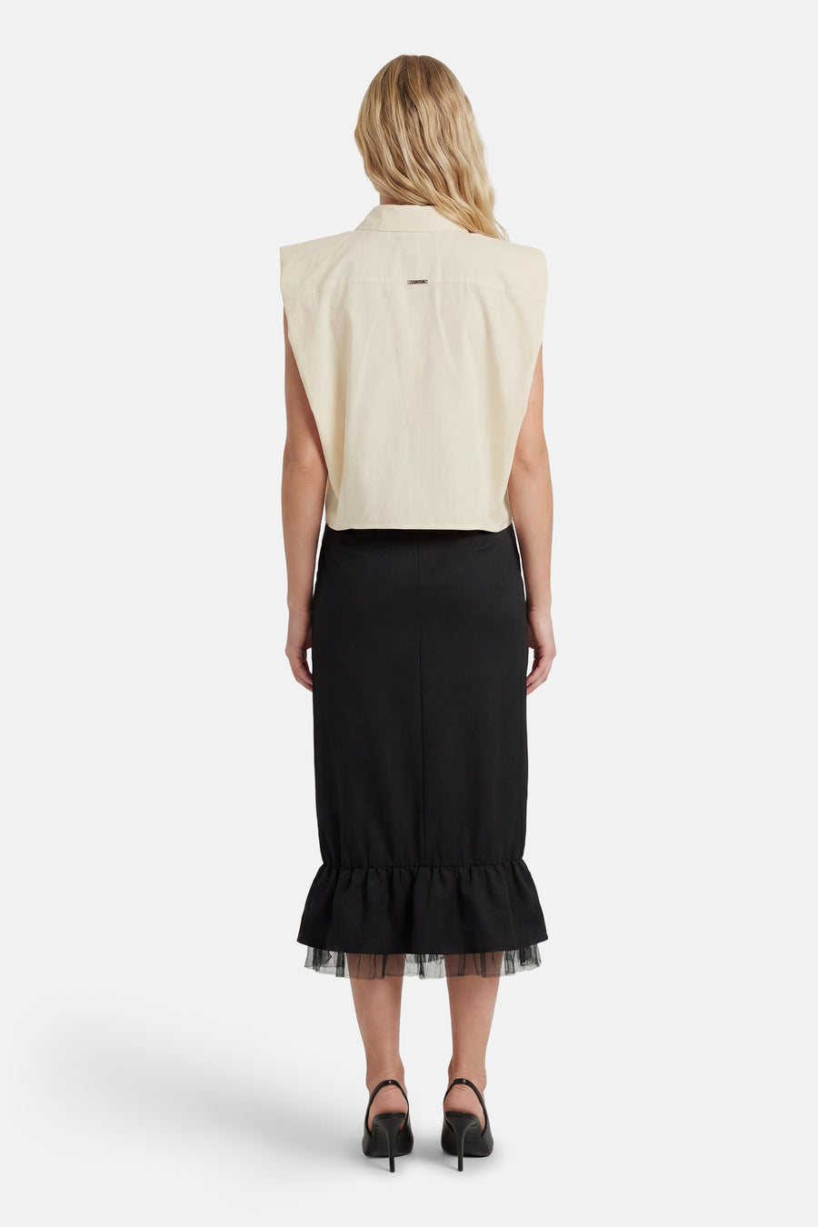 Chemisier sans manches beige de GOA GOA avec petite plaque dorée au dos, porté avec une jupe noire à volants en tulle, vue de dos.