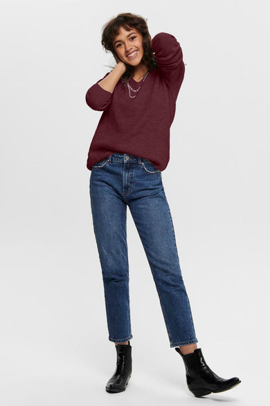 Pull à col en V bordeaux de ONLY, porté avec un jean bleu et des bottines noires.